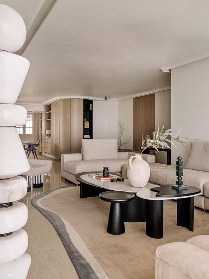 The living room of Kanso House, seen from behind a sculptural floor lamp, highlighting the layers of texture and form in the space.