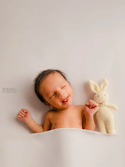 A playful, candid moment with an awake newborn making a funny face next to a small knitted bunny toy. These simple, unposed shots are perfect for capturing your baby's unique quirks.
