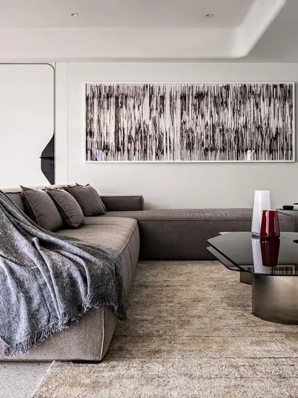 A detail of the informal living area in Apartment 56, where a deep lounge sofa and abstract art create a comfortable yet curated space. The design prioritizes clean lines and a focus on the expansive feel of the room.