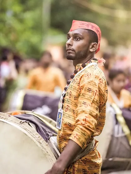 The color version of the dhol player's profile, his red cap standing out.
