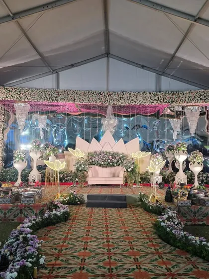 A modern and glamorous stage setup in a tent, with a lotus-petal backdrop and crystal chandeliers.