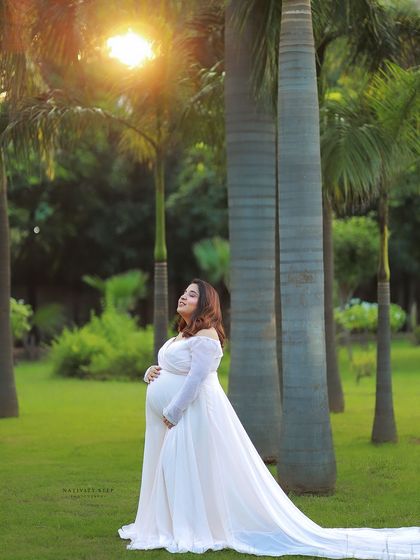 A dreamy outdoor portrait in a white gown with a long train. The golden sunlight filtering through the palm trees creates a breathtaking, ethereal glow.