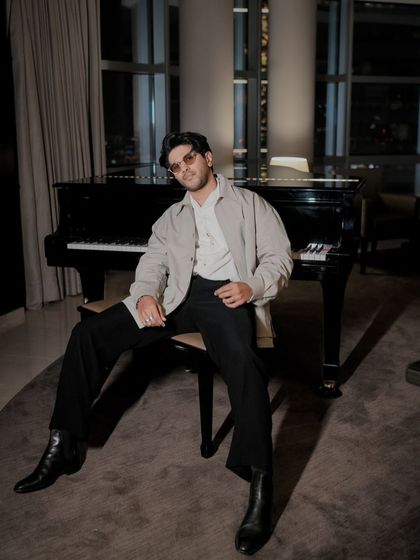 The full look for Dulquer Salmaan's Dubai promotions. The relaxed silhouette, pointed boots, and grand piano create a sophisticated, artistic vibe.