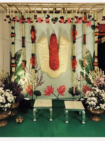 An elegant Pellikuthuru decor setup featuring the sacred Tirupati namam made of flowers. The backdrop and floral arrangements are designed to create a divine atmosphere for the bridal ceremony.