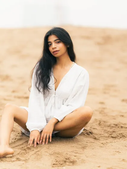 A relaxed, seated pose on the sand. This feels natural and approachable, great for lifestyle or personal branding photos.