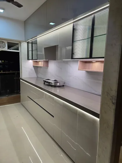 This linear kitchen showcases a beautiful high-gloss, lacquered finish that reflects light and creates a sense of space. We've incorporated fluted glass cabinets and integrated LED strip lighting under the counter for both task lighting and ambiance.