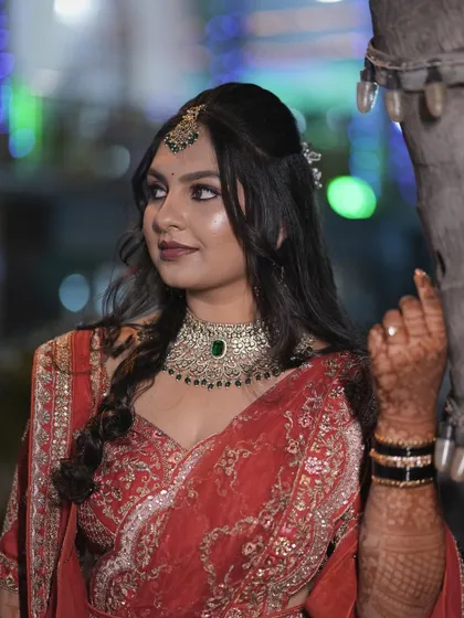A candid side profile of the bride at her reception. The hairstyle is a soft, wavy half-updo that complements her modern lehenga.