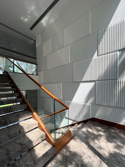 The sunlight creates beautiful shadows on the textured wall panels of the Gulmohar Farmhouse staircase, turning a simple wall into a piece of art that changes throughout the day.