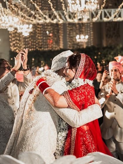 The perfect backdrop for a perfect moment. This image captures the couple's embrace, surrounded by the warm glow of fairy lights and the love of their family and friends.