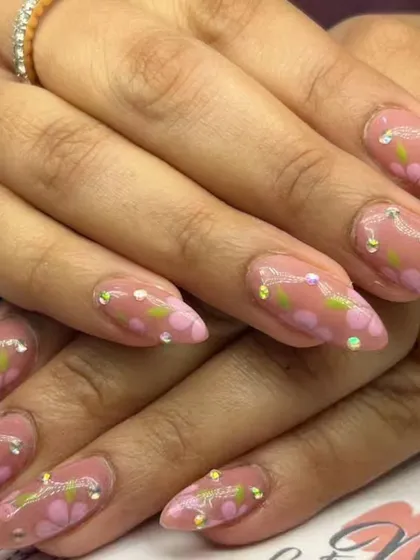 A lovely floral design with hand-painted pink flowers and green leaves on a nude base, accented with tiny sparkling rhinestones.