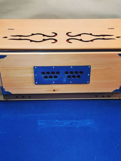 A side view of the camel-colored harmonium, highlighting its sturdy wooden construction and classic design. This instrument is perfect for both practice and performance settings.
