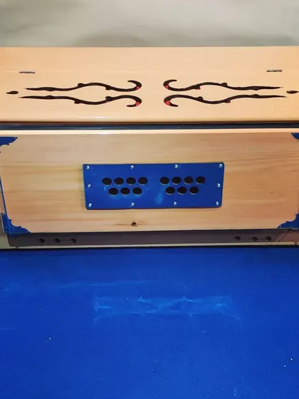 A side view of the camel-colored harmonium, highlighting its sturdy wooden construction and classic design. This instrument is perfect for both practice and performance settings.