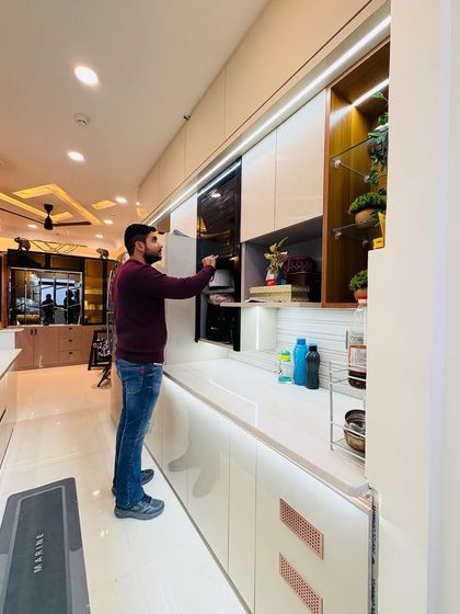 Checking the functionality of the built-in microwave and storage units in this sleek modular kitchen. Every detail is planned for convenience and ease of use.