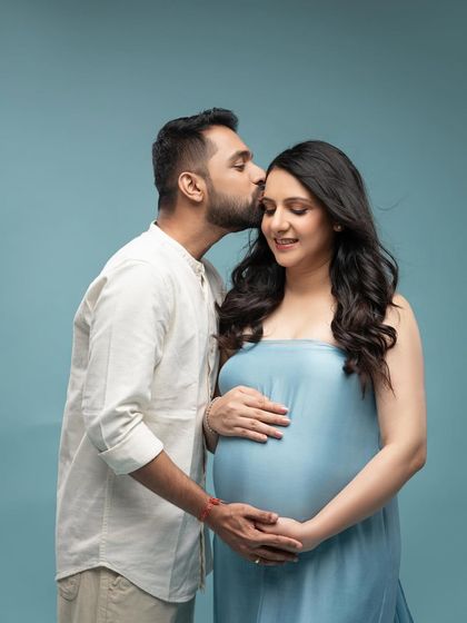A sweet forehead kiss, a classic pose that is always full of emotion. The soft blue color palette is serene and calming.