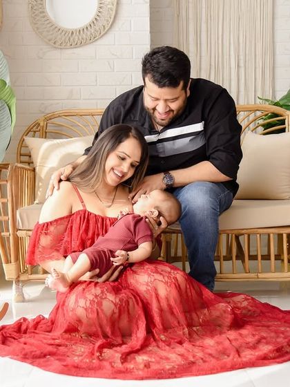 A playful and loving family moment with their baby. The mother cradles the baby in her lap while the father looks on, creating a beautiful composition full of warmth and affection.