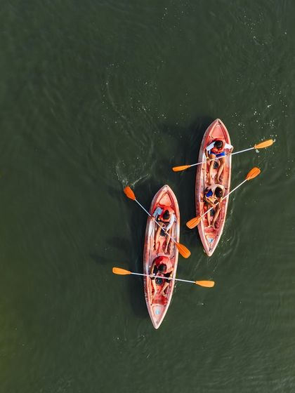 The perfect summer activity. An aerial shot of two kayaks gliding across the serene green water of the lake.