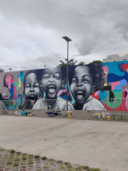 The mural in context with other artworks at the festival, showing a blend of our abstract style with hyperrealism.