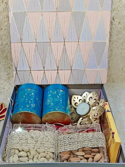 A premium Diwali gift box containing two decorative tins, two boxes of assorted nuts, and a lotus-shaped candle holder.