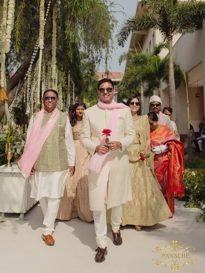 The groom's procession, with his family walking alongside him, holding a single red rose.