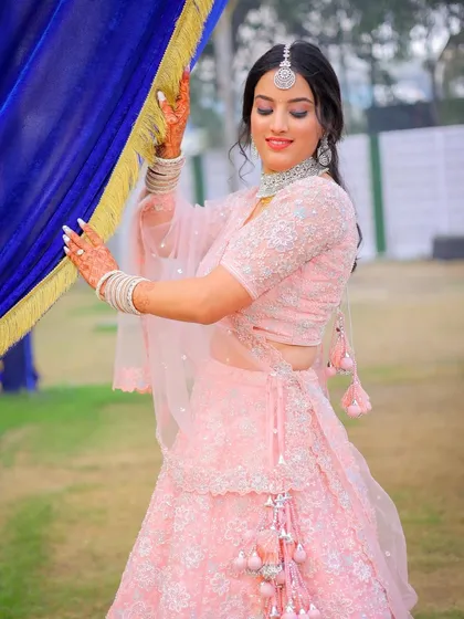 An outdoor portrait session with a bride in a lovely pink lehenga, using the location's decor to frame the shot.