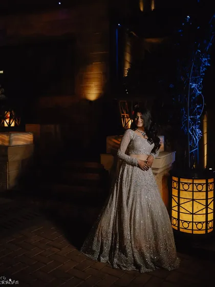 A full-length bridal portrait at night, with dramatic lighting creating a moody and elegant atmosphere.