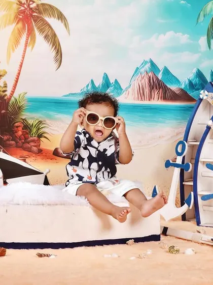 Fun and creative themed photoshoots are one of my specialties. For this pre-birthday session, we created a vibrant beach scene right in the studio, complete with a boat, sand, and sunglasses for little Naksha to enjoy. These shoots are all about capturing your child's personality.
