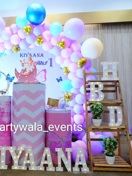 A close-up of the beautiful details in this butterfly first birthday party, including the moon prop and the themed "HBD" shelf.