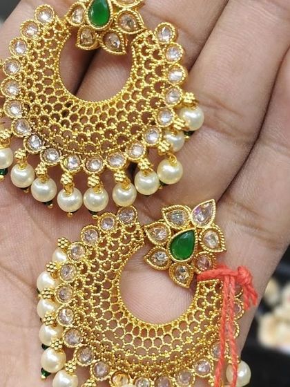 A pair of light-weight gold-look chandbali earrings with green stones and pearls.