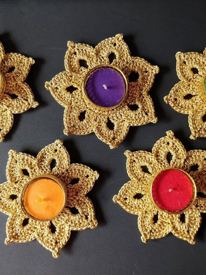 A top-down view of five golden tea light holders with colorful candles. They look stunning arranged together on a table.