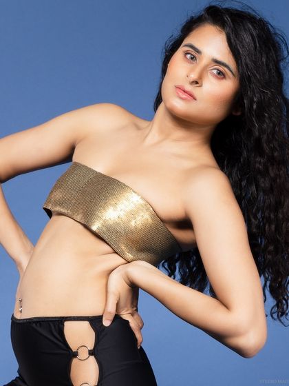 A close-up of the model in a gold top, with a dynamic and engaging pose.
