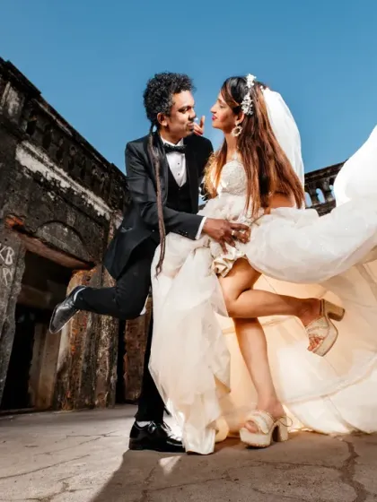 A playful and energetic moment during a post-wedding shoot at a historic fort. The groom's joyful kick and the bride's flowing dress capture the fun and excitement of the day.