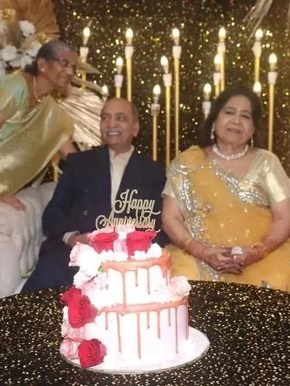 The happy couple celebrating 50 years together, about to cut their anniversary cake in front of the glamorous backdrop I designed for their special day.