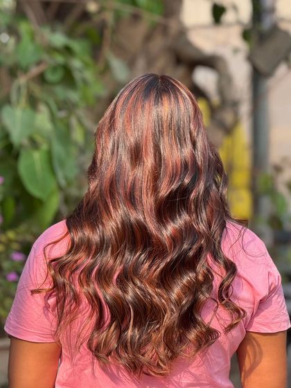 A stunning back view of long, wavy hair with vibrant highlights. The color is rich and dimensional, creating a look that is sure to turn heads.