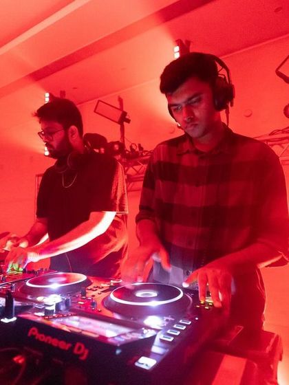 Two DJs focused on their craft, mixing under the intense red lights of the ballroom. We provide a platform for both established and emerging domestic acts to showcase their talent.