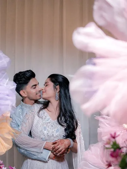 We created a whimsical backdrop with giant, handmade paper flowers in pastel shades for Yash and Sakshi's couple shoot, resulting in artistic and romantic portraits.