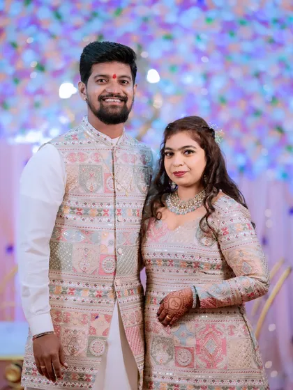 A formal portrait of a couple in stunning, coordinated embroidered outfits for their engagement ceremony.