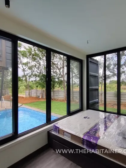 A bedroom with a pool view in a container home, showing how large windows can create a resort-like feel.