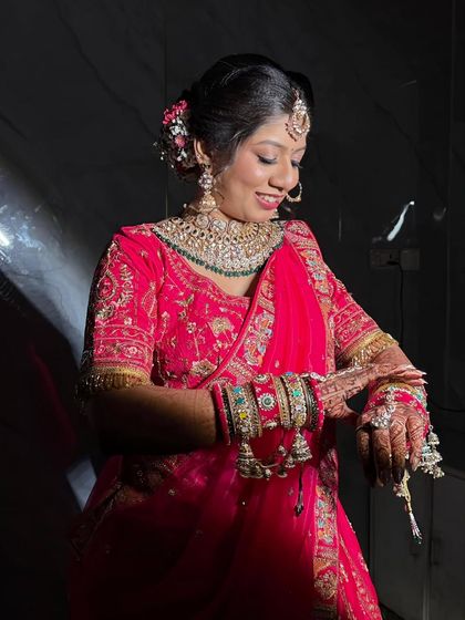 This candid shot captures the bride's joy. The makeup remains flawless as she adjusts her bangles, showing the durability and elegance of her look.