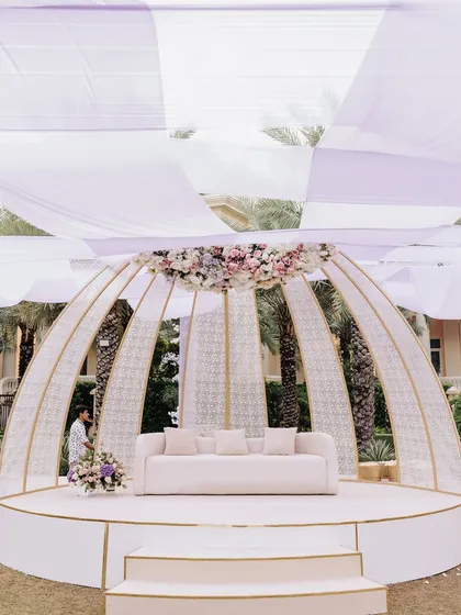 A modern, dome-shaped stage structure, elegantly decorated with a floral crest, providing a chic and sophisticated backdrop.