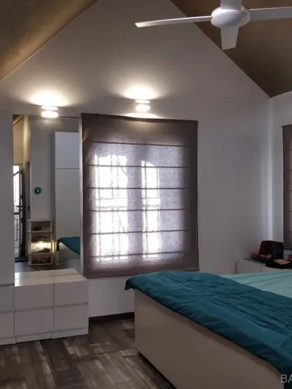 We designed this bedroom with a vaulted ceiling, using smart storage solutions and simple window treatments to create a bright and airy feel.