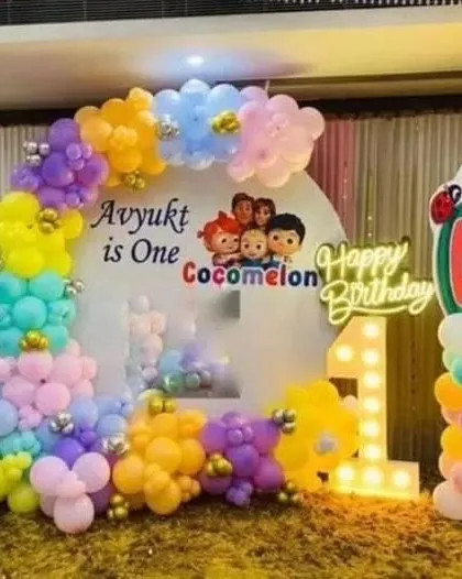A cute and simple Cocomelon theme for a first birthday. The backdrop features characters from the show and a colorful balloon frame.