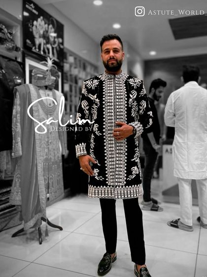 A client in a long black jacket with heavy, all-over silver embroidery, worn over black trousers. This creates a powerful, modern ethnic look.