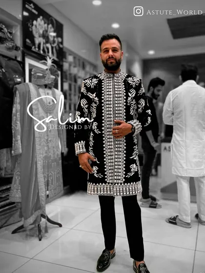 A client in a long black jacket with heavy, all-over silver embroidery, worn over black trousers. This creates a powerful, modern ethnic look.