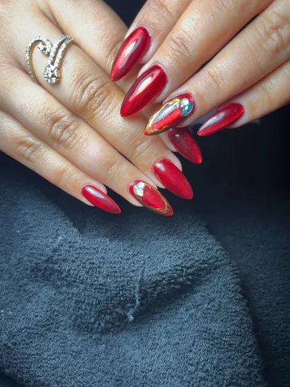 A striking set of long, red stiletto nails with gold and crystal accents for a touch of luxury.