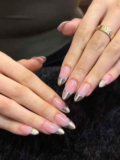 A modern classic. These nails feature a sharp, stiletto almond shape with a clean, natural pink base and futuristic liquid-metal silver chrome tips for a sleek and edgy French manicure.