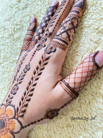 A close up of a design featuring multiple patterns on the fingers, including crisscross nets, leafy vines, and floral bands.