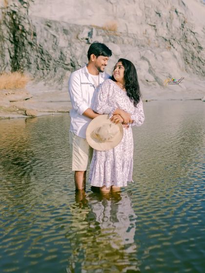 A couple wades into the calm water of a quarry lake, sharing a loving gaze. The reflection in the water adds a beautiful symmetry to the shot.