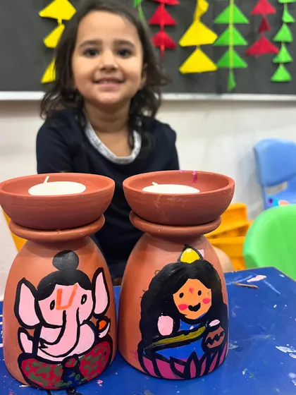 A sweet, out-of-focus shot capturing a young child's pride in her painted Diwali diyas.