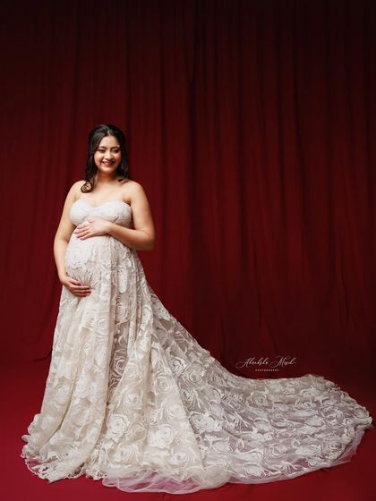A smiling portrait in a beautiful white lace gown against a rich red backdrop, creating a lovely and striking contrast.