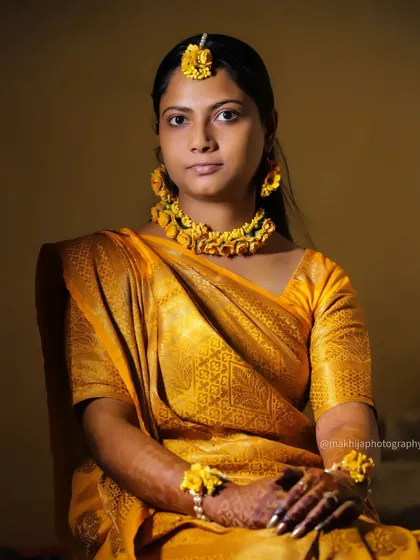 A simple and elegant portrait of the bride in her Haldi attire. The direct gaze and confident smile show her readiness and excitement for the wedding festivities.